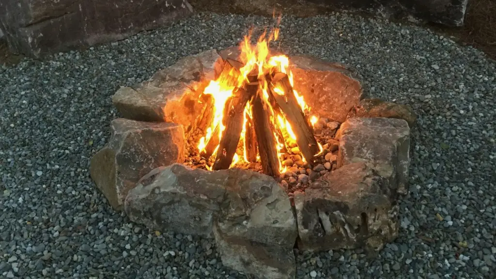 Loc de foc amenajat din pietre mari, pe pietriș, cu focul aprins